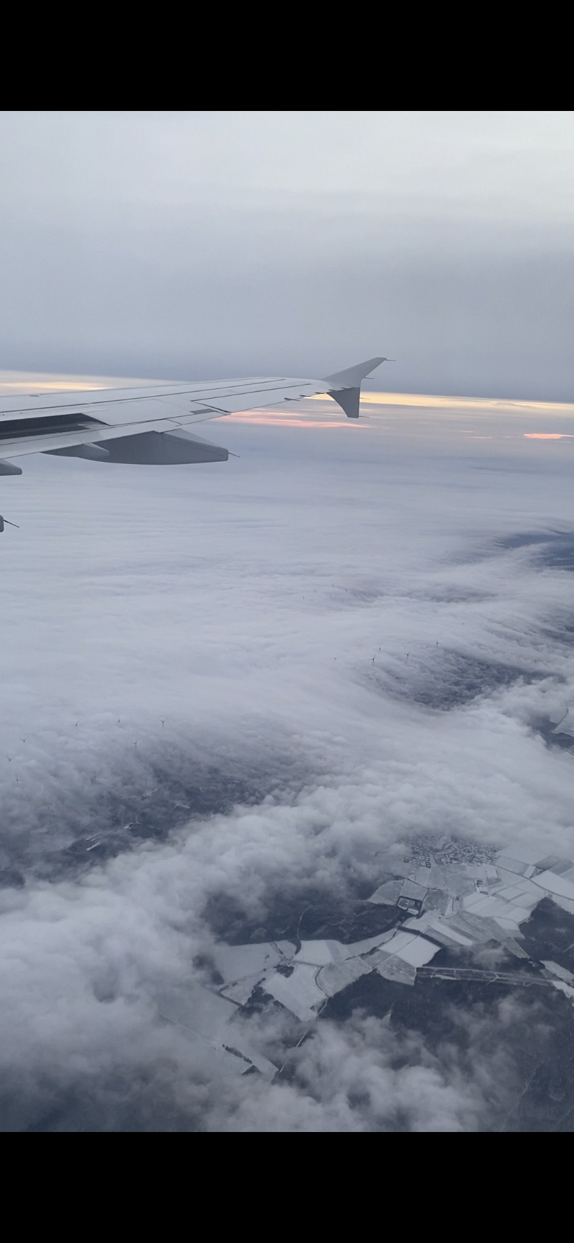 Auf diesem Bild ist ein Flugzeug über den Wolken zu sehen.
